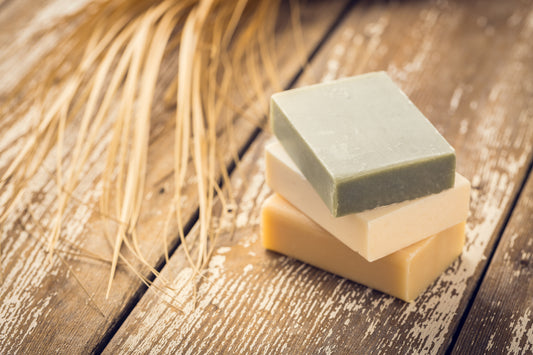 Three natural soap bars stacked on a wooden table.