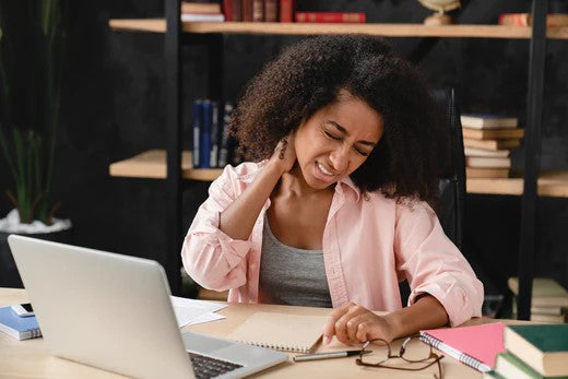 A woman with fibromyalgia sitting at her desk with her laptop