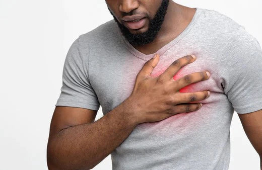 A man clutching his chest in pain, experiencing a heart attack. Learn how to reduce your risk of heart disease.