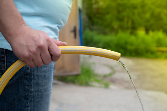 A man holding a hose, water flowing out.