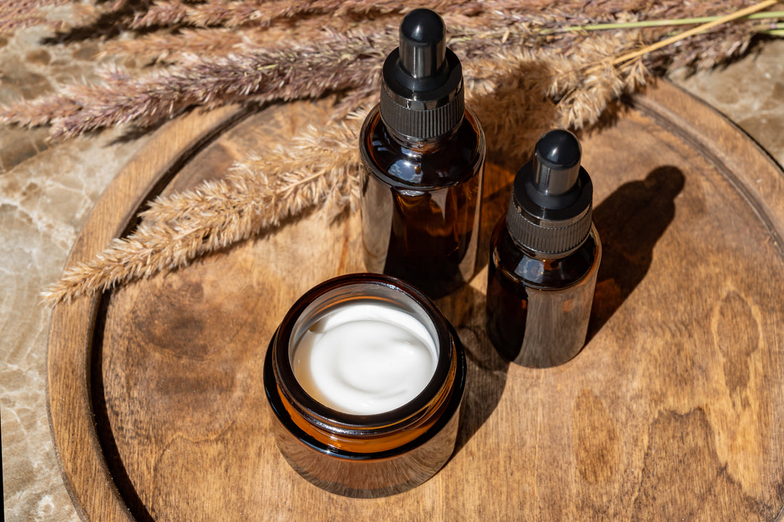 Set of amber glass with bear butter and beard oil bottles on wooden tray