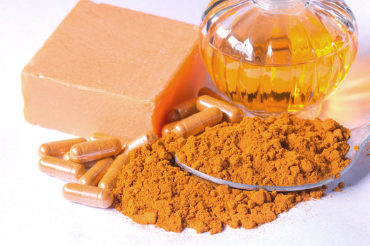 Turmeric powder on a spoon beside a bottle of vitamin, used for creating turmeric soap.