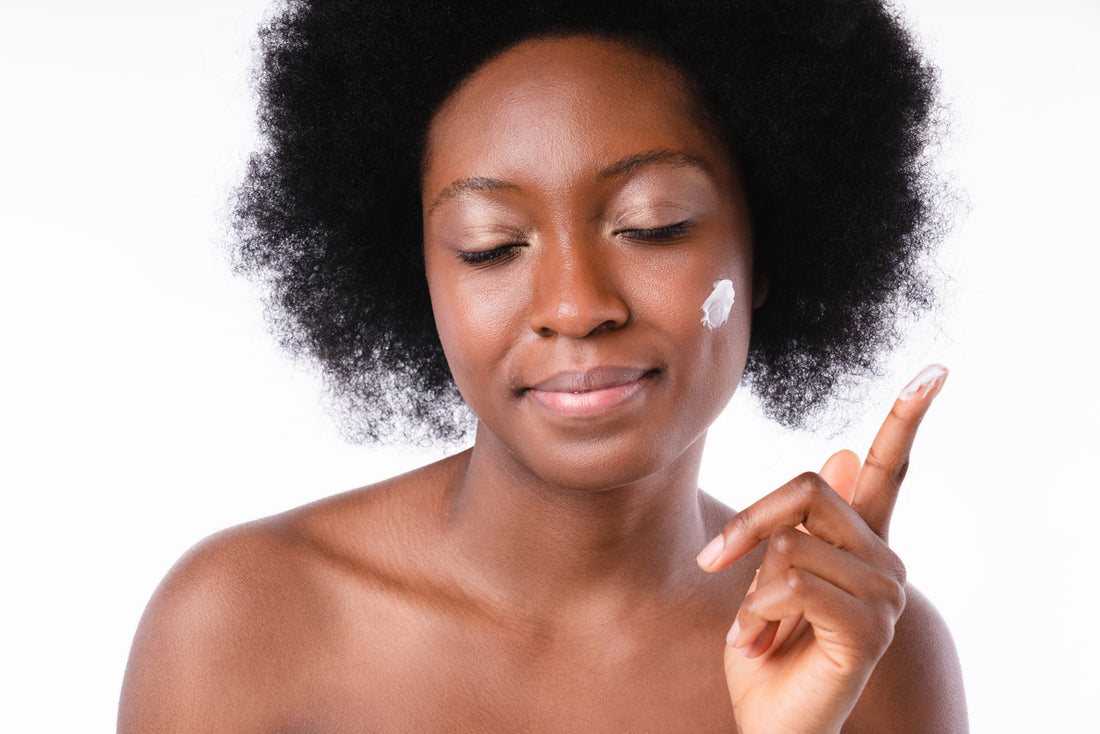 Cropped portrait of an african young girl with facial cream over white background