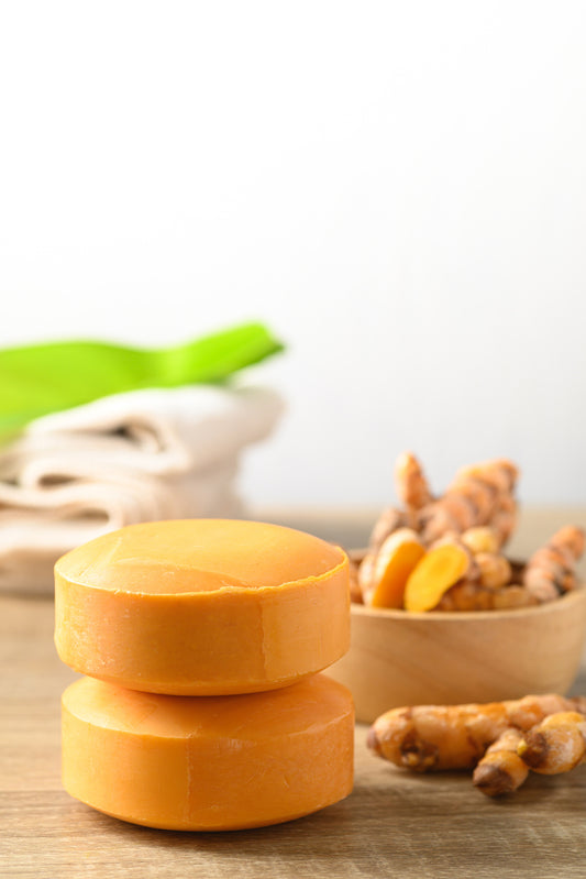 A bowl of TURMERIC soap and a bowl of turmeric sitting side by side.