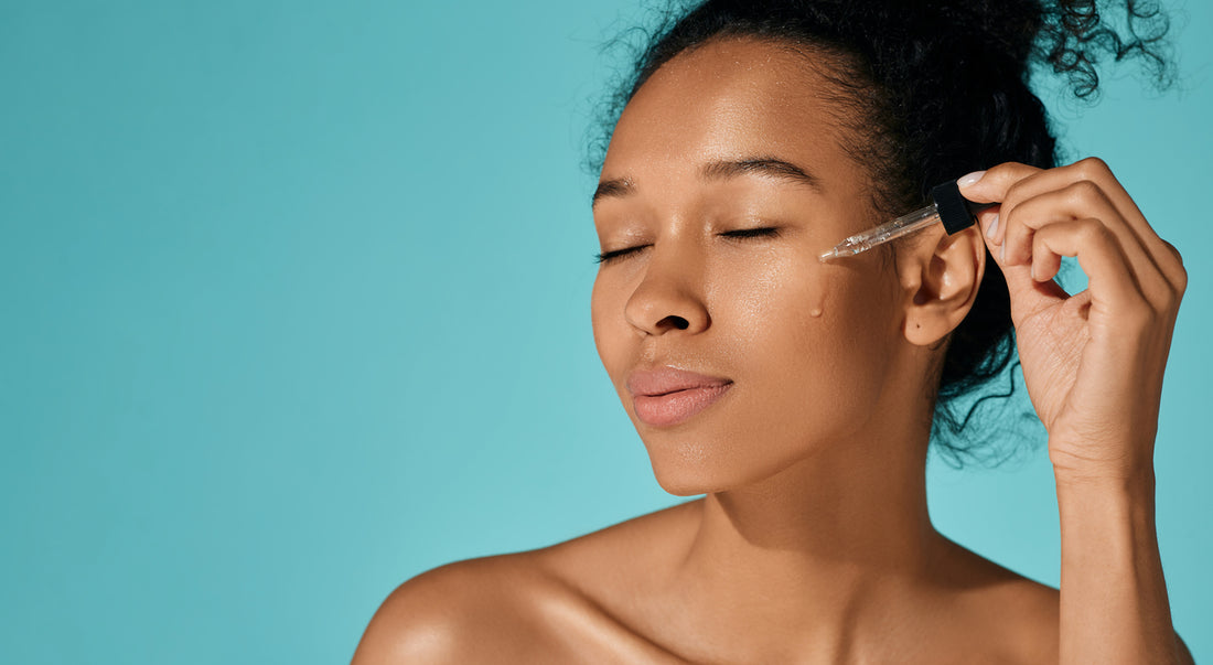 Happy African woman applying Hyaluronic Acid Serum on her face for hydrated skin with pipette dropper,