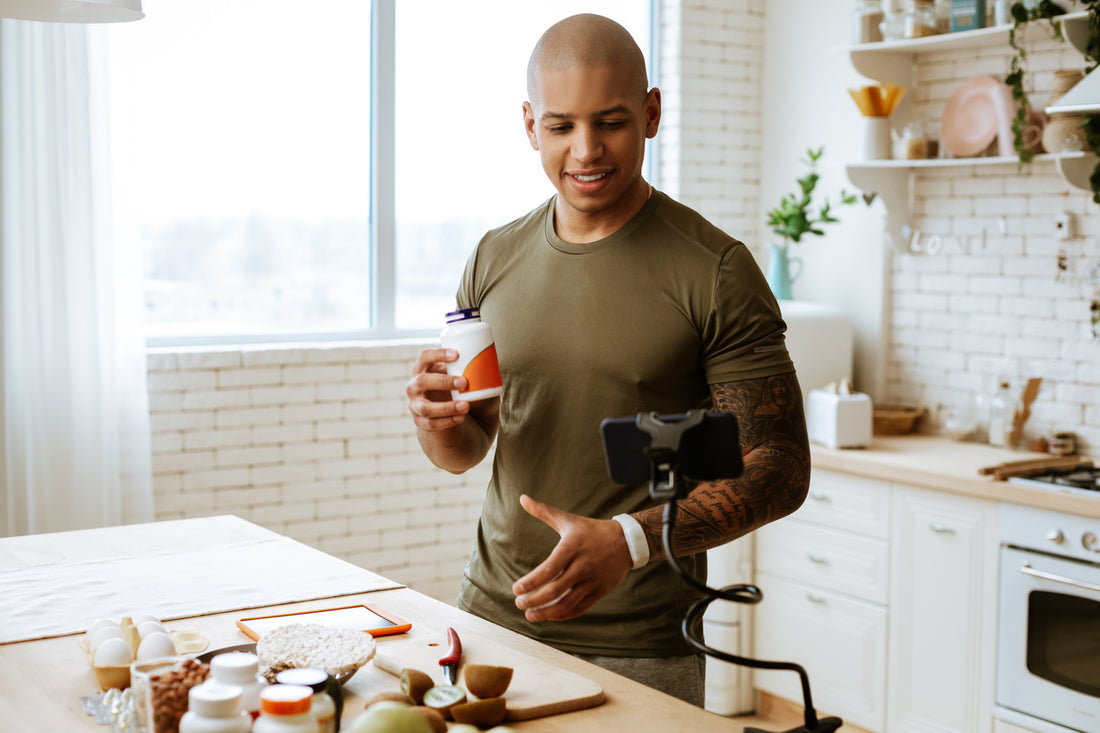 A man holding a bottle of supplement in a kitchen, representing supplements for men.