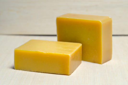 Two bars of turmeric soap bar on a wooden plank