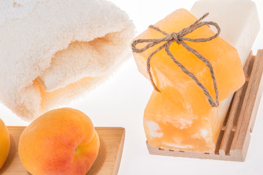 stack of apricot soap bars, apricot fruits and towel on white