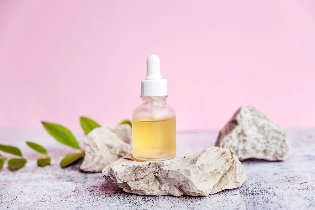 A bottle of essential oil on a rock, containing anti-aging ingredients.