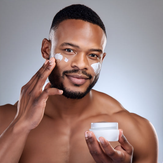 Handsome black man applying moisturizing cream to face