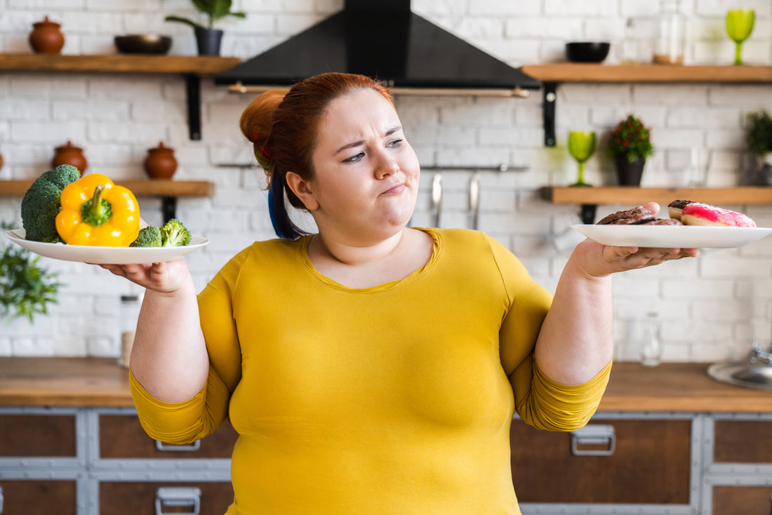 A woman holds two plates with different foods on them, representing the metabolic confusion diet plan.