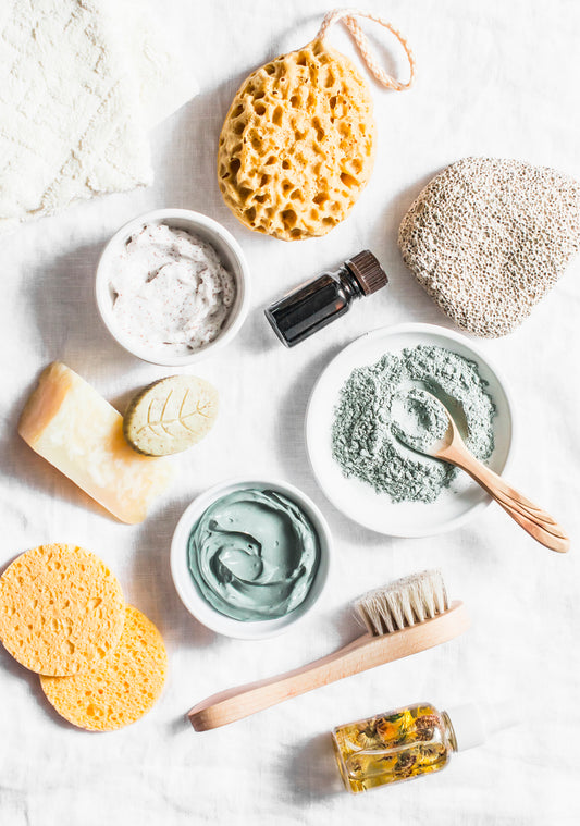 Assorted skin care products on white cloth, including natural exfoliating scrubs.