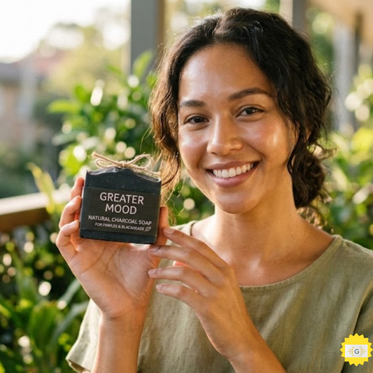 person with glowing skin holding a Greater Mood natural charcoal soap bar for pimples and blackheads